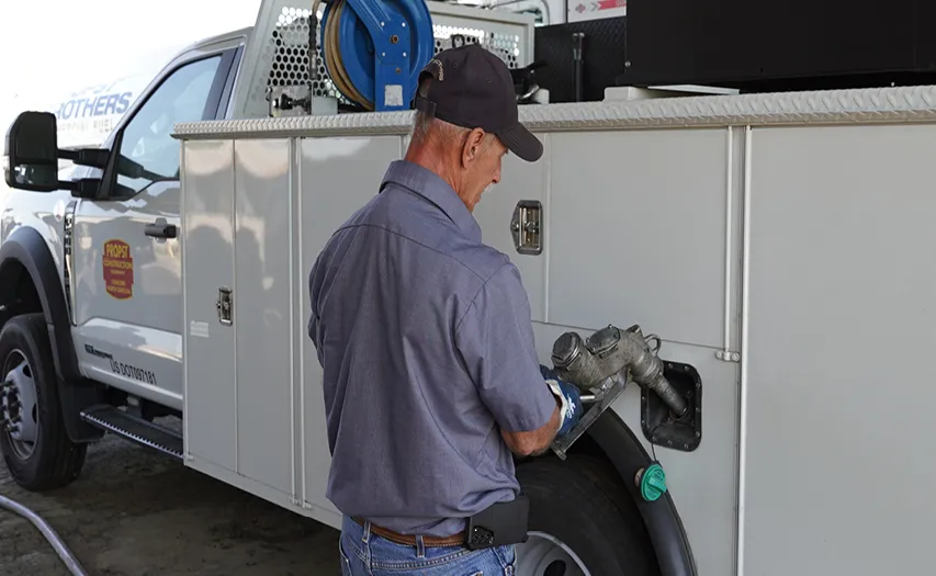 Ray Chisholm connecting fuel hose to service truck for on-site commercial fuel delivery.