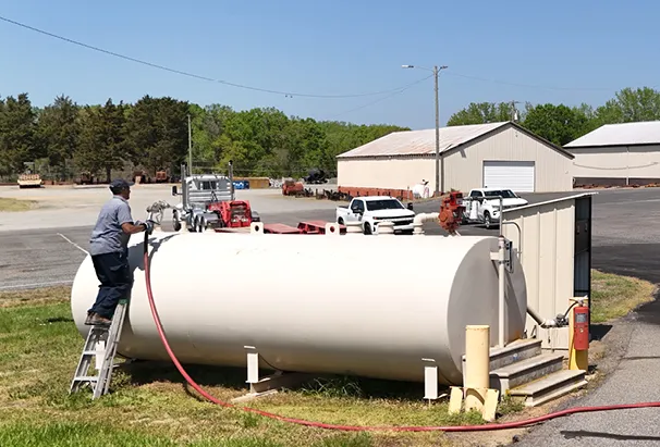 Technician fueling an on-site storage tank using Propst Brothers fuel delivery truck.