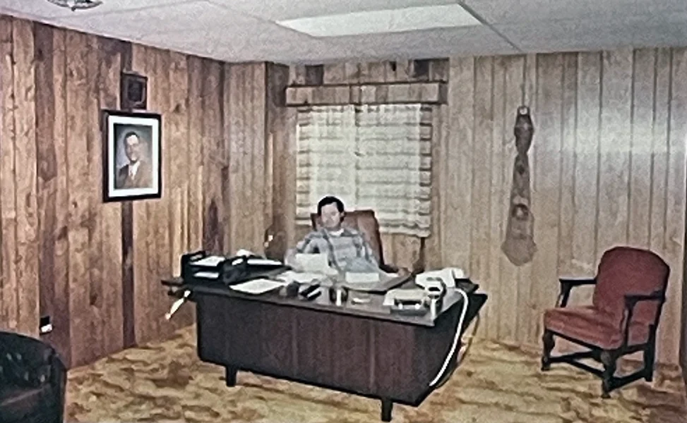 Vintage photo of Joe Propst Jr. seated at a desk inside the original wood-paneled Propst Brothers office.