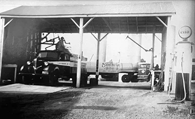 Vintage fuel station with early delivery trucks and pumps representing the early history of Propst fuel operations.